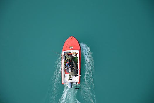 pexels-photo-240561-240561-1 Top view of a red motorboat with fishermen navigating open turquoise waters.
