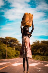 A young girl carries a container of water on a rural road in Lodwar, Kenya.